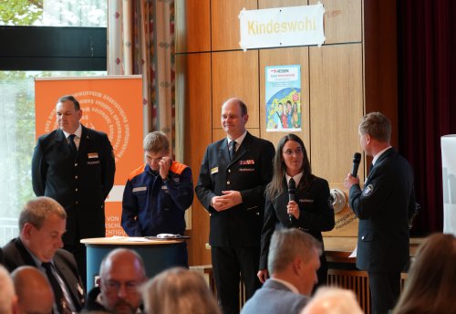 Mehrere Personen stehen auf der Bühne unter dem Schild „Kindeswohl“ und werden interviewt, eine Person hält das Mikrofon