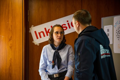 Junge Frau im Dienstanzug im Gespräch mit einem jungen Mann vor einem Plakat mit der Aufschrift „Inklusion“
