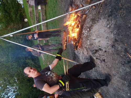 Teilnehmer sitzen am Abend am Lagerfeuer am Zeltplatz