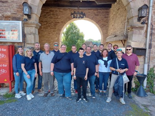 Gruppenfoto der Teilnehmenden beim Ausflugsprogramm „Blick in den Landkreis" unter einem steinernen Torbogen