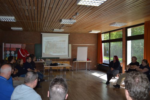Workshop in einem hellen Saal, ein Referent erläutert eine Präsentation auf der Leinwand