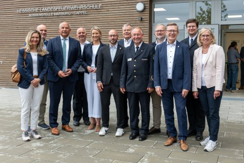 Gruppe von Gästen und Vertreter:innen aus Politik und Feuerwehr vor dem Gebäude der Hessischen Landesfeuerwehrschule Außenstelle Marburg-Cappel