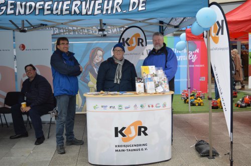 Drei Männer am Infostand des Kreisjugendrings Main-Taunus unter dem Banner „...gendfeuerwehr.de"