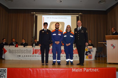 Ehrung dreier junger Mitglieder in Feuerwehruniform auf der Bühne