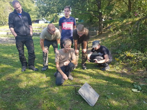Gruppe beim Versuch, mit einem Stein und einem Stock Funken zu schlagen