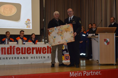 Übergabe einer gerahmten Weltkarte auf der Bühne als Erinnerung an eine internationale Jugendbegegnung