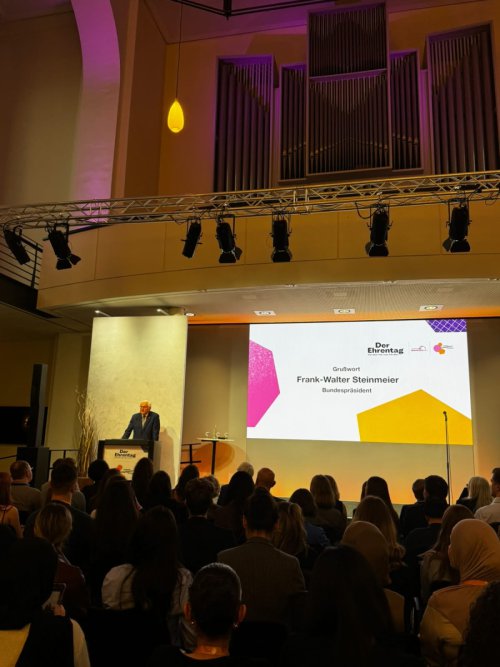 Bundespräsident Frank-Walter Steinmeier am Rednerpult beim „Ehrentag“; auf der Leinwand sein Name und der Hinweis Grußwort