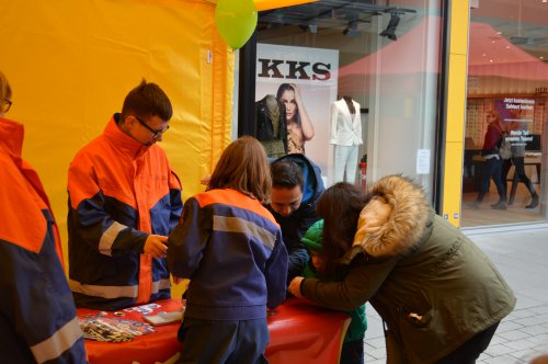 Jugendfeuerwehr-Mitglieder in oranger Schutzkleidung betreuen Kinder und Erwachsene an einem Mitmachstand