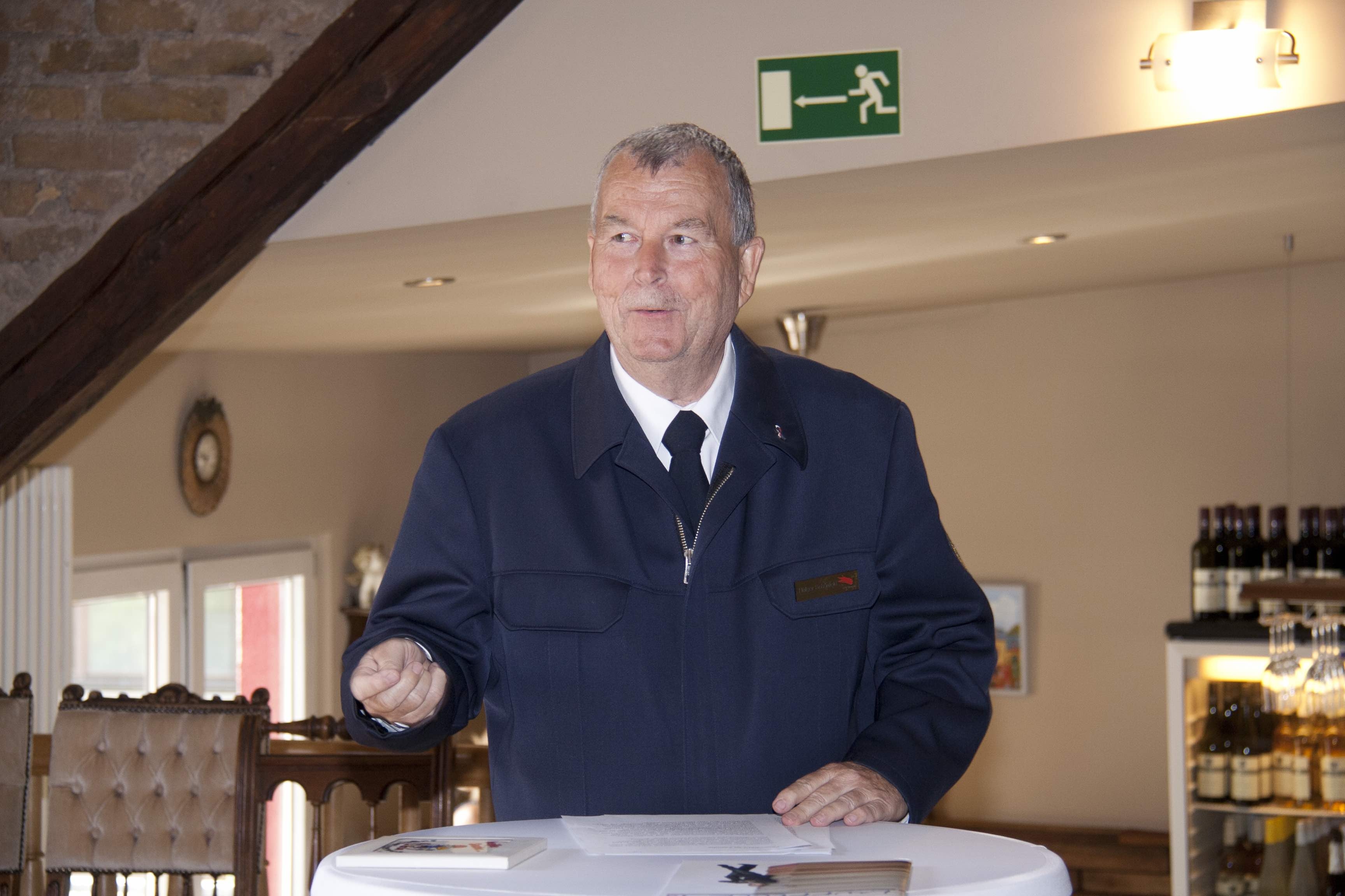 Holger Schönfeld in dunkelblauer Feuerwehruniform spricht an einem Stehtisch in einem festlichen Raum