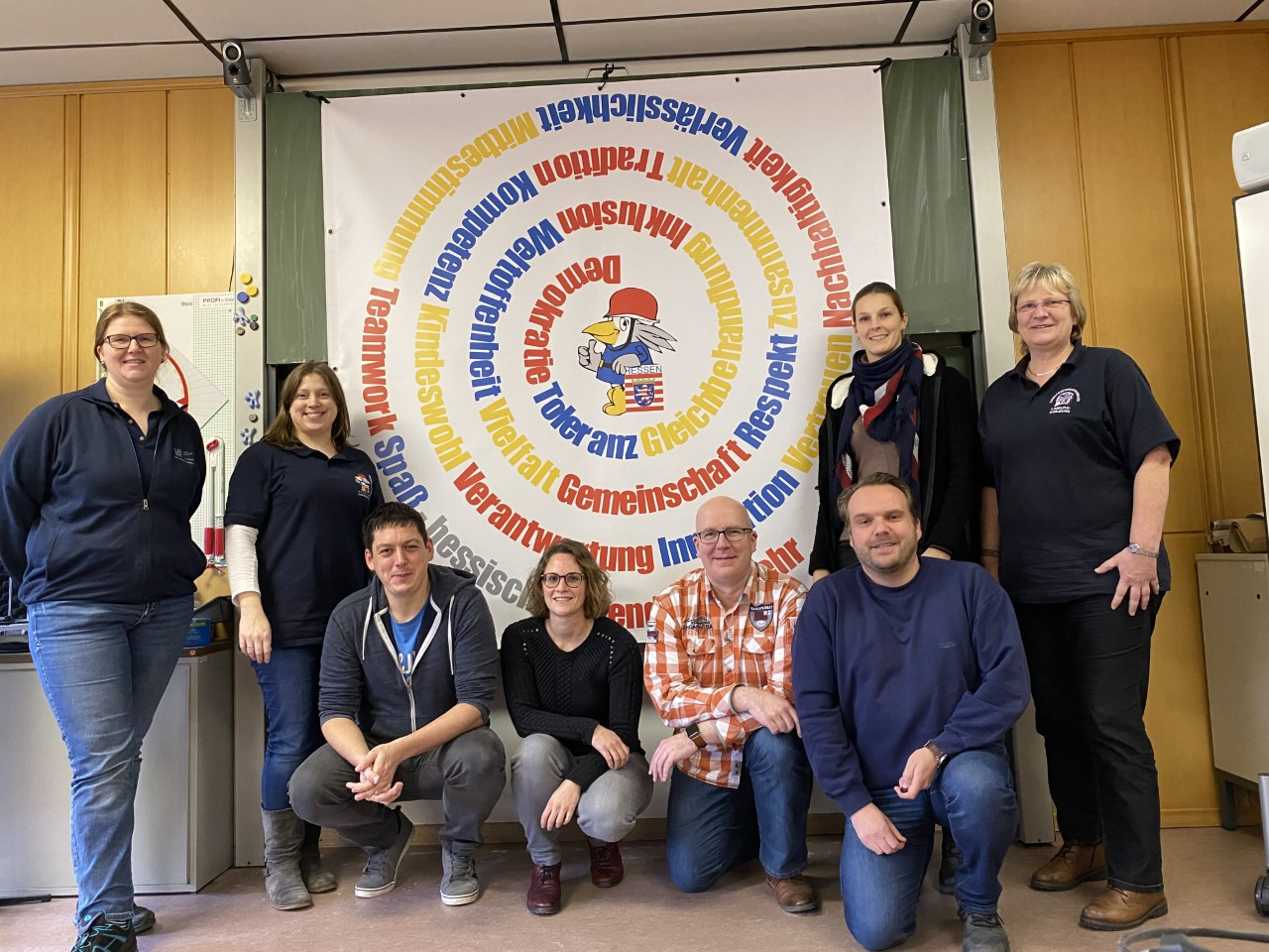 Gruppenbild der AG Polarisierung vor einem Banner mit der spiralförmig angeordneten Wertespirale der Jugendfeuerwehr