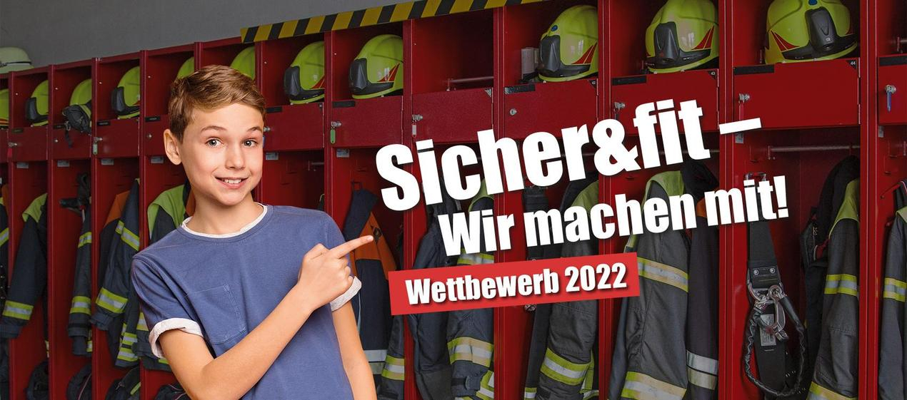 Lächelnder Junge im blauen T-Shirt vor einer Reihe roter Feuerwehr-Spinde mit Helmen und Schutzkleidung, daneben der Schriftzug „Sicher&fit – Wir machen mit! Wettbewerb 2022"