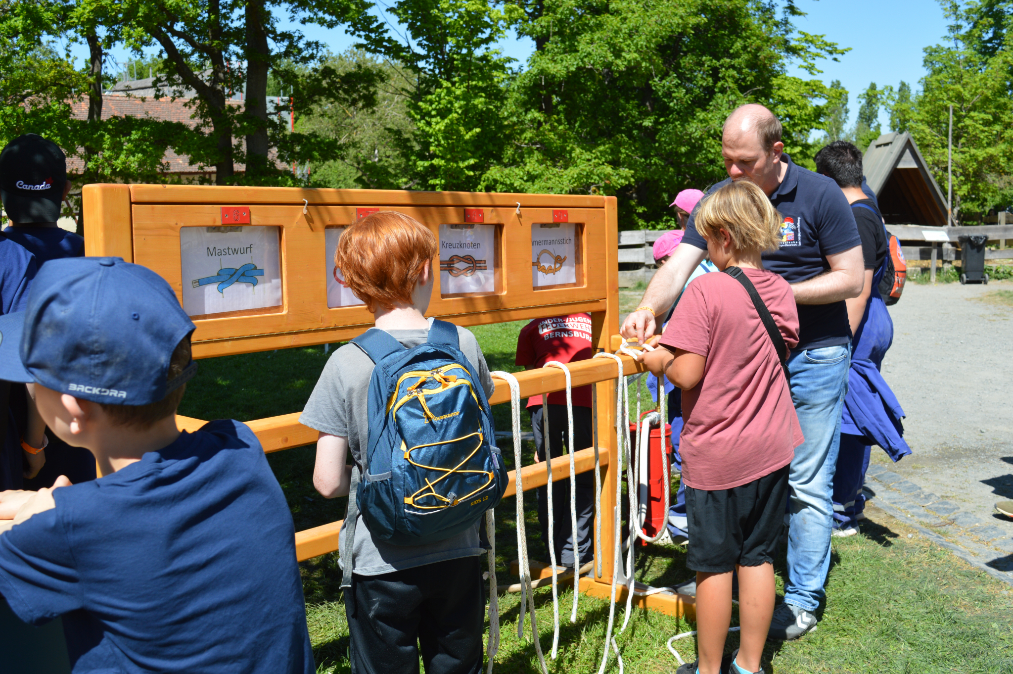 Kinder und Jugendliche spielen an einer hölzernen Mitmach-Station mit Wurfspielen auf einer sonnigen Wiese im Hessenpark