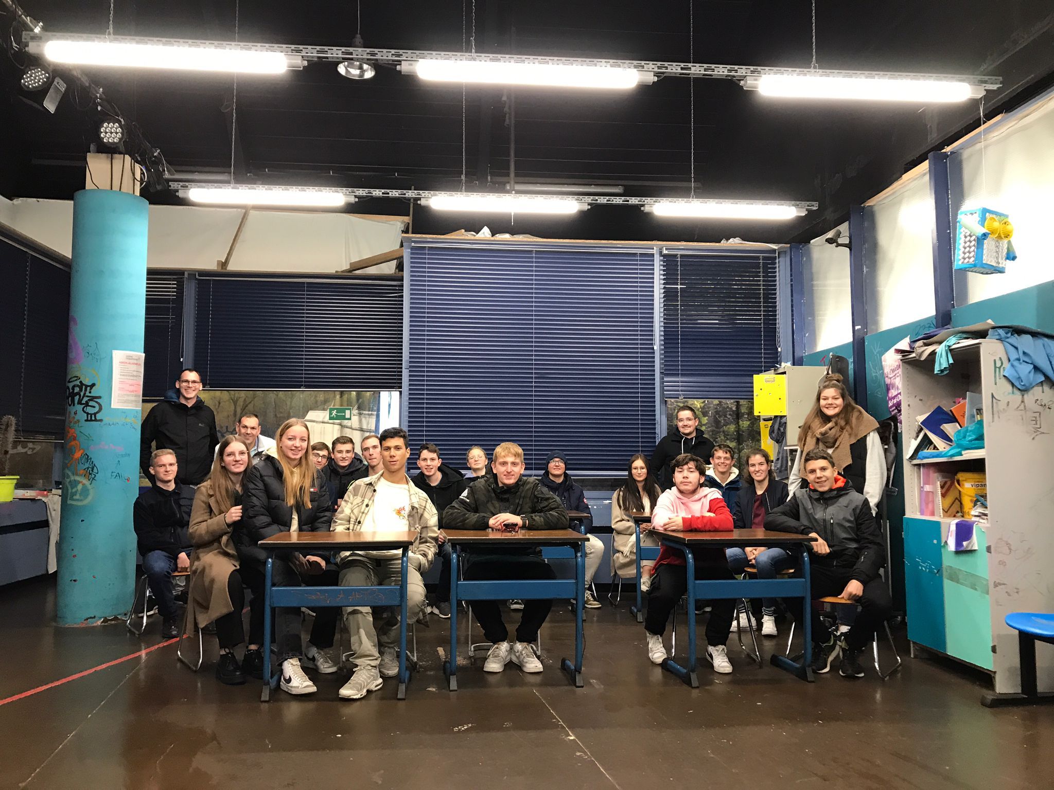 Gruppenfoto der Jugendforum-Mitglieder an Tischen in einem Jugendherbergsraum während der Fahrt nach München