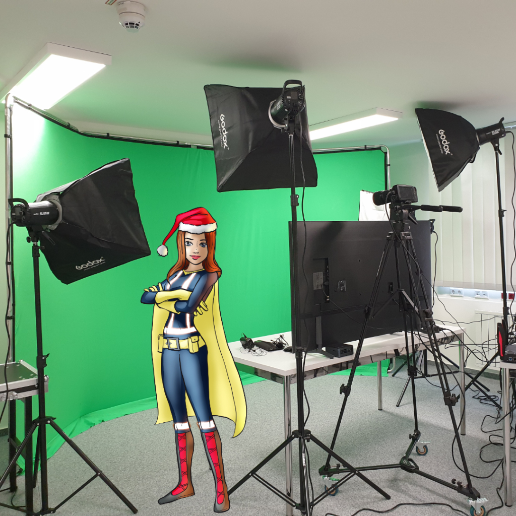 Greenscreen-Filmstudio mit mehreren Studioleuchten und Kamera, davor die illustrierte Maskottchen-Heldin mit gelbem Umhang und Weihnachtsmütze